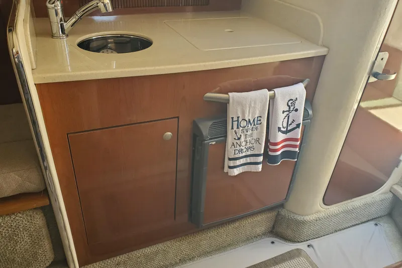 Slide: The Image of 2008 Sea Ray Sundancer 280 interior with kitchenette, sink, and nautical-themed towels. - 17