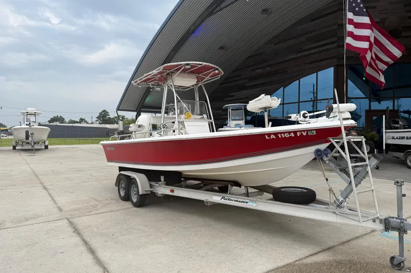 Slide: The Image of 2005 Sea Pro SV2100CC Bay Boat on trailer, parked near a building with an American flag. - 2