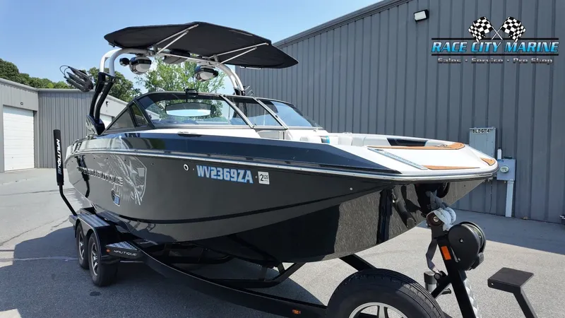 Slide: The Image of A black 2015 Nautique G23 boat on a trailer in front of a gray building. - 5