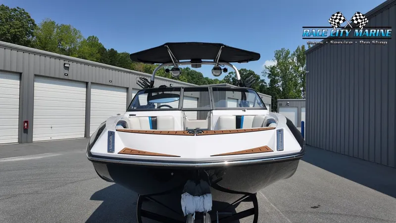 Slide: The Image of A 2015 Nautique G23 boat on a trailer in front of garages. It features a black canopy. - 3