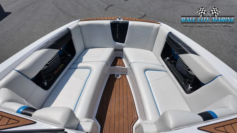 Slide: The Image of The image shows the bow area of a 2015 Nautique G23 with white upholstery and wood flooring. - 35