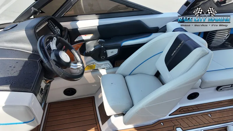 Slide: The Image of The image shows the helm of a 2015 Nautique G23 with a white seat and wooden flooring. - 33