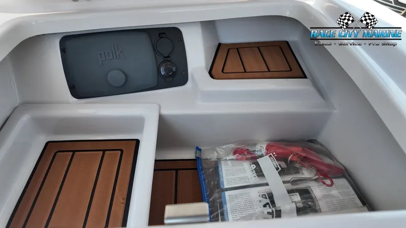 Slide: The Image of The image shows a storage compartment in a 2015 Nautique G23 boat with wood paneling. - 19