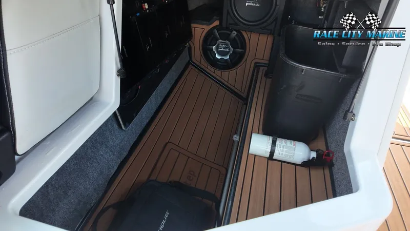 Slide: The Image of The image shows the interior of a 2015 Nautique G23 with wood flooring and speakers. - 23