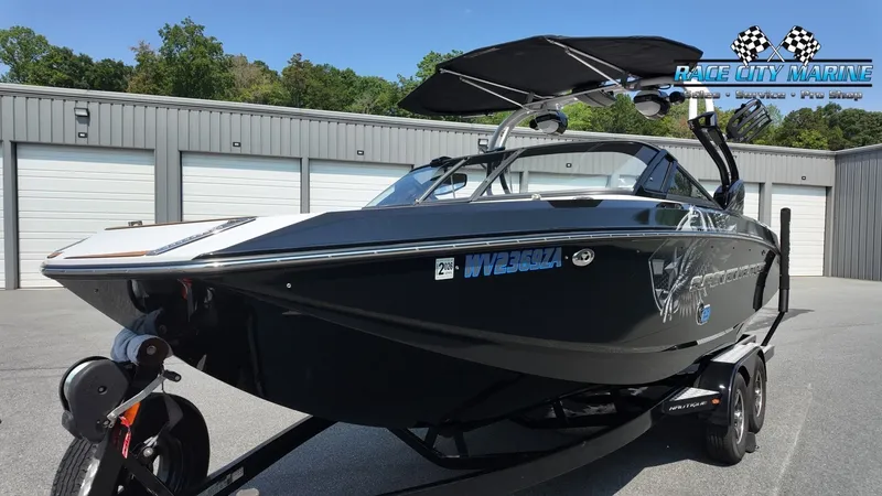 Slide: The Image of A black 2015 Nautique G23 boat on a trailer in front of garages. - 6