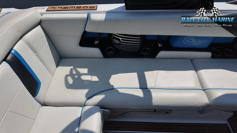 Slide: The Image of The image shows the interior of a 2015 Nautique G23 with white upholstery and blue accents. - 20