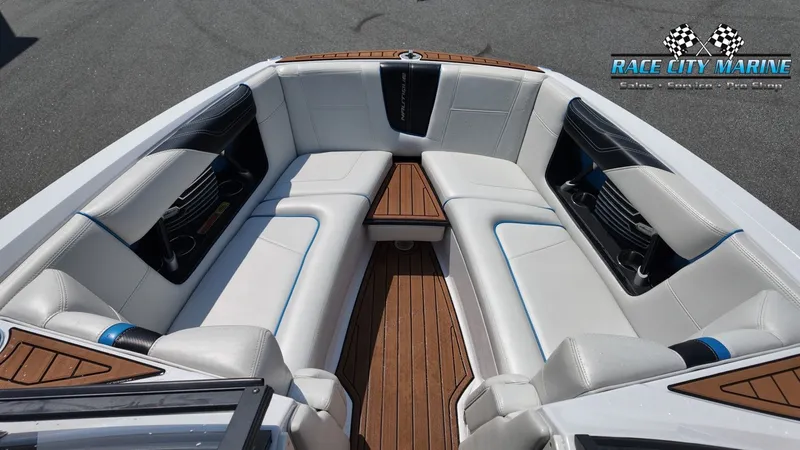 Slide: The Image of The image shows the bow area of a 2015 Nautique G23 boat with white upholstery and wood flooring. - 25