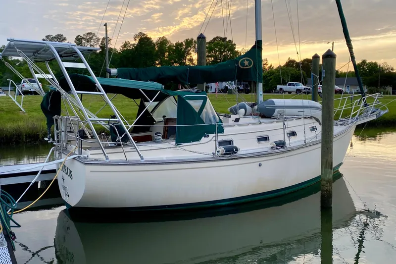 The Image of 1992 Island Packet 29 sailboat docked at sunset, featuring green canvas covers. - 0