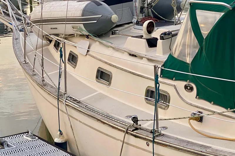 Slide: The Image of 1992 Island Packet 29 sailboat docked, featuring green canvas cover and inflatable dinghy. - 17