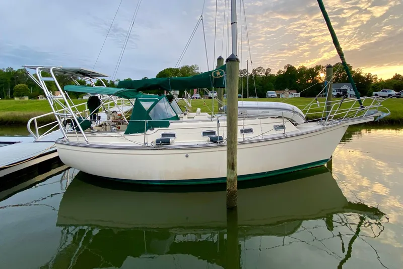 Slide: The Image of 1992 Island Packet 29 sailboat docked, featuring green canvas covers and polished metal railings. - 4