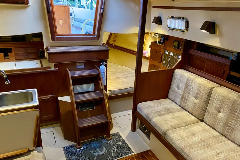 Slide: The Image of Interior of a 1992 Island Packet 29 sailboat, featuring cozy seating and wooden cabinetry. - 45