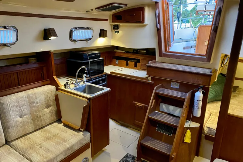 Slide: The Image of Interior of a 1992 Island Packet 29 sailboat, featuring a cozy kitchen and seating area. - 47