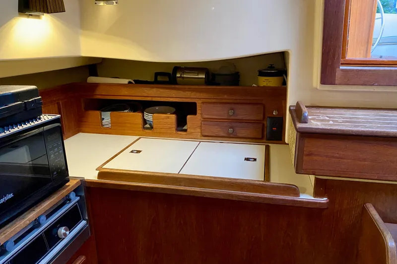 Slide: The Image of 1992 Island Packet 29 yacht interior galley with wooden cabinetry and modern appliances. - 50
