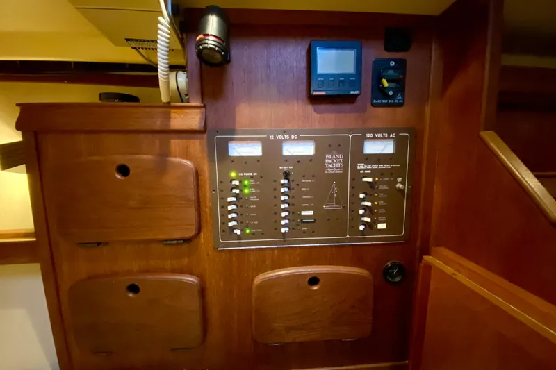 Slide: The Image of Electrical control panel on a 1992 Island Packet 29 yacht, featuring DC and AC switches. - 53