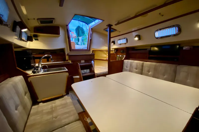 Slide: The Image of Interior of a 1992 Island Packet 29 sailboat, featuring a cozy dining area and kitchenette. - 62