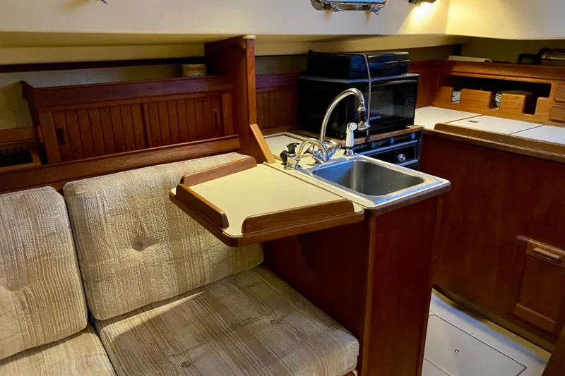 Slide: The Image of Interior of 1992 Island Packet 29 sailboat with compact kitchen and seating area. - 64