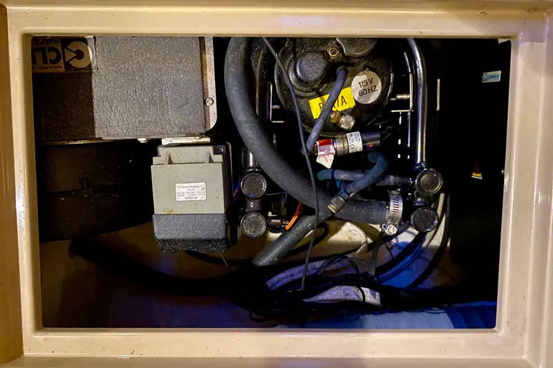 Slide: The Image of Engine compartment of a 1992 Island Packet 29 sailboat, showing mechanical components and hoses. - 86