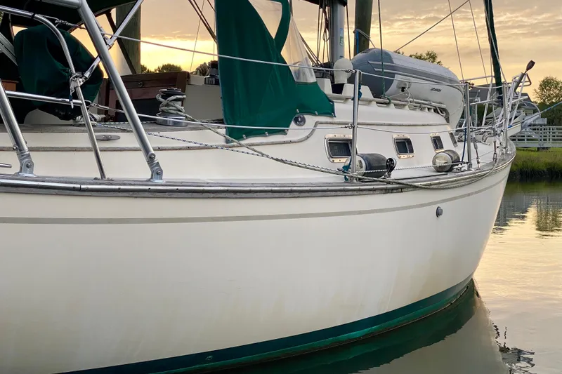 Slide: The Image of 1992 Island Packet 29 sailboat docked at sunset, featuring green canvas covers. - 9