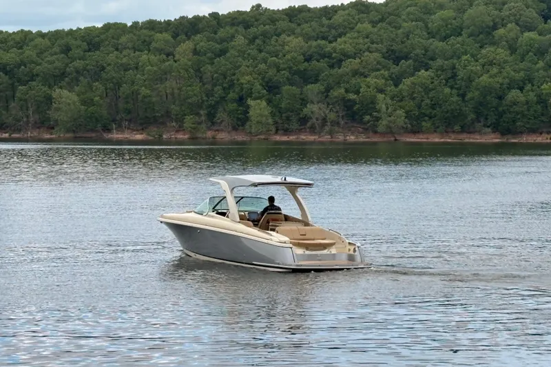 The Image of 2026 Chris-Craft Launch 31 GT cruising on a serene lake with lush forest backdrop. - 0