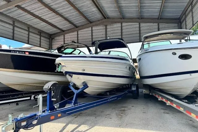 The Image of 2024 Crownline 290 SS boat on trailer, parked under a metal canopy. - 0