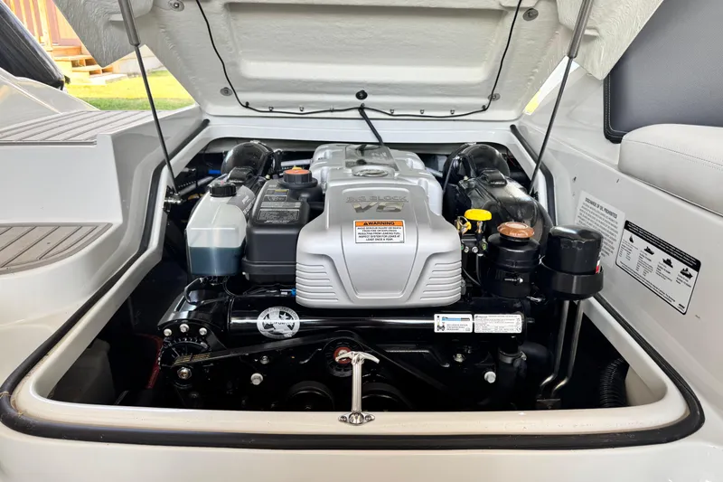 Slide: The Image of 2024 Crownline 290 SS boat engine compartment with open hatch, showcasing engine components. - 13