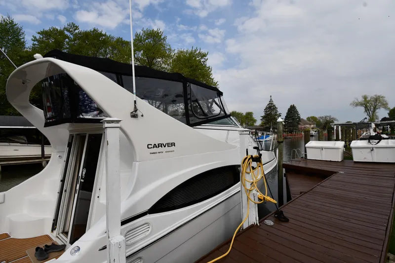 Slide: The Image of 2000 Carver 350 Mariner docked, featuring sleek design and spacious deck under a cloudy sky. - 3