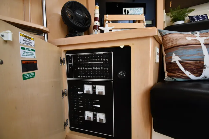 Slide: The Image of Electrical panel inside a 2000 Carver 350 Mariner yacht, featuring safety labels and nautical decor. - 49