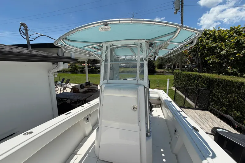 Slide: The Image of 2005 Competition 25 boat with T-top, docked near a house, under clear blue skies. - 15