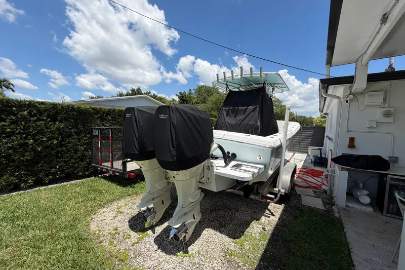 Slide: The Image of 2005 Competition 25 boat with dual engines on a trailer, parked outdoors. - 2