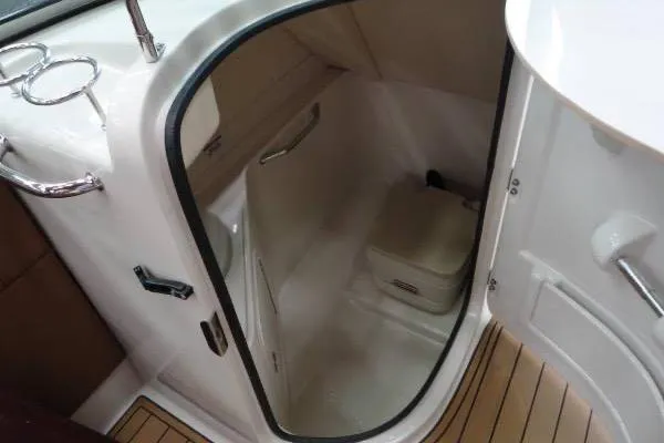 Slide: The Image of 2007 Sea Ray 260 Sundeck boat interior with compact restroom and wooden flooring. - 14