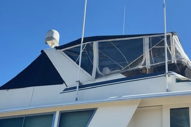 Slide: The Image of 1983 Hatteras 53 Extended Deckhouse Motor Yacht with enclosed upper deck against blue sky. - 2