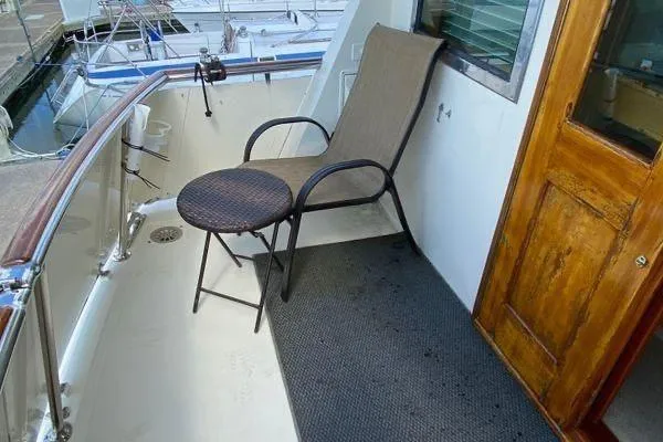Slide: The Image of 1983 Hatteras 53 Motor Yacht deck with chair and table, docked at marina. - 26