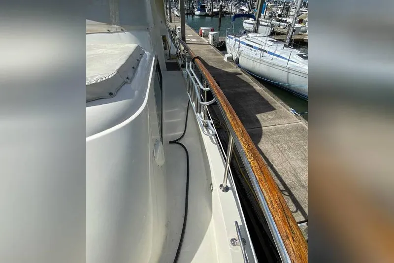 Slide: The Image of 1983 Hatteras 53 Extended Deckhouse Motor Yacht docked, showcasing sleek deck and polished railings. - 37
