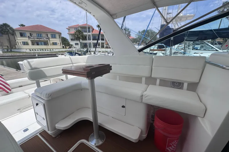 Slide: The Image of 2001 Tiara Yachts 3500 Open interior with white seating and wooden table in marina setting. - 19