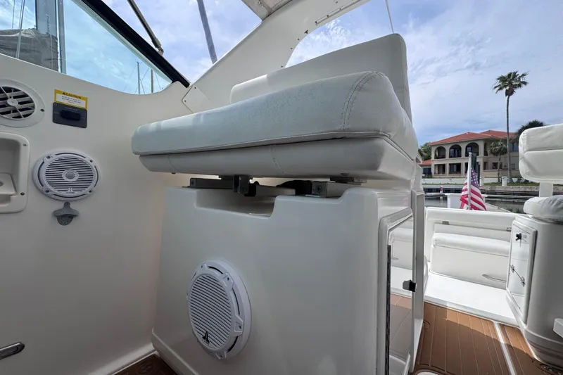 Slide: The Image of 2001 Tiara Yachts 3500 Open cockpit with white seating and speakers, docked near waterfront homes. - 21