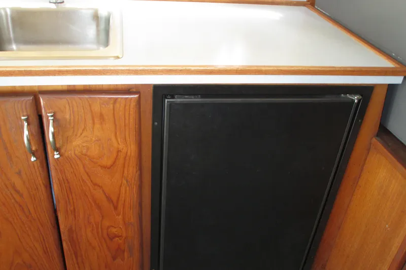 Slide: The Image of 1972 Uniflite 36 Sport Sedan kitchen with wooden cabinets and a compact refrigerator. - 17