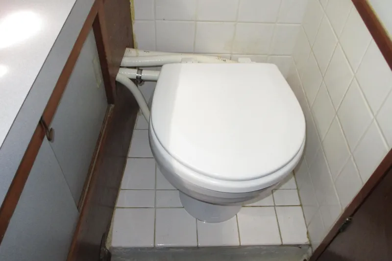 Slide: The Image of 1972 Uniflite 36 Sport Sedan bathroom with white toilet and tiled walls. - 30