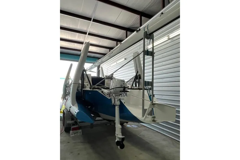 Slide: The Image of 1996 Farrier F-25C trimaran stored indoors, featuring folded amas and outboard motor. - 10