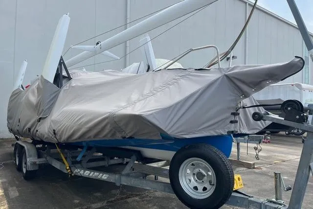 Slide: The Image of Covered 1996 Farrier F-25C sailboat on trailer, parked near a large building. - 6