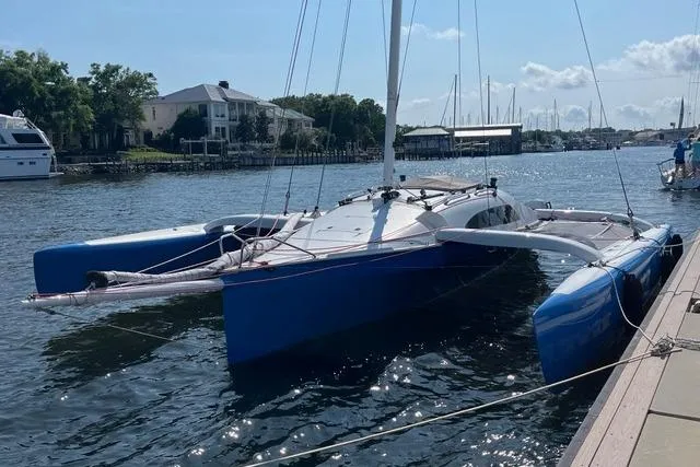 Slide: The Image of 1996 Farrier F-25C trimaran docked in a marina, featuring blue hulls and white deck. - 7