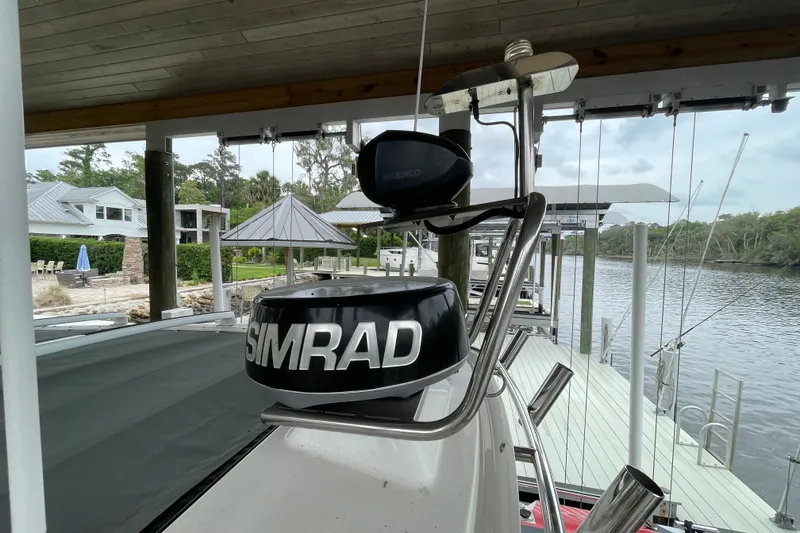 Slide: The Image of 2021 Axopar 28 Cabin with Simrad radar, docked by a scenic waterfront. - 15