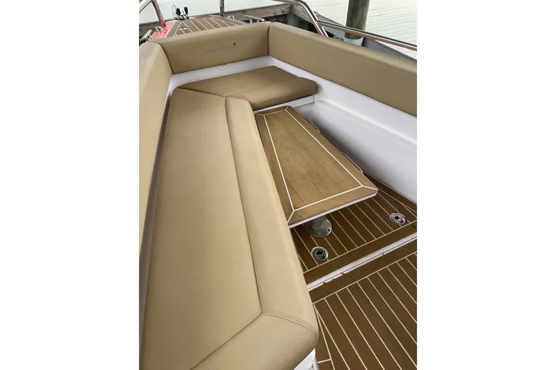 Slide: The Image of 2021 Axopar 28 Cabin interior with tan seating and wooden table. - 18