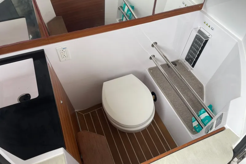 Slide: The Image of 2021 Axopar 28 Cabin bathroom with toilet, sink, and storage shelves. - 19