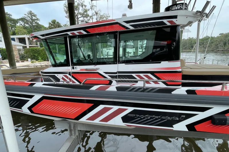 Slide: The Image of 2021 Axopar 28 Cabin boat with striking red, black, and white geometric design. - 2