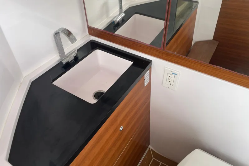 Slide: The Image of 2021 Axopar 28 Cabin bathroom sink with modern faucet and wood accents. - 20