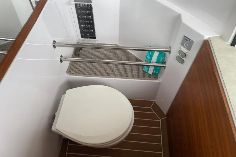 Slide: The Image of 2021 Axopar 28 Cabin bathroom with toilet, wooden accents, and modern fixtures. - 21