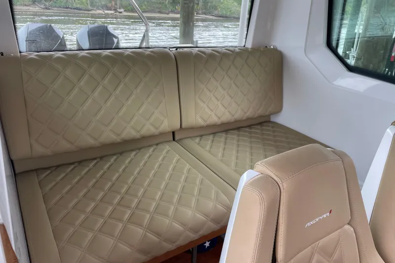 Slide: The Image of Luxurious interior of 2021 Axopar 28 Cabin with quilted beige seating. - 28