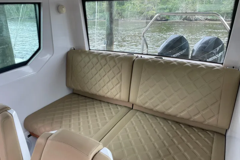 Slide: The Image of Interior of 2021 Axopar 28 Cabin with beige quilted seating and Mercury engines visible. - 30