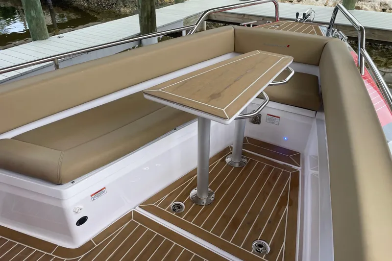 Slide: The Image of 2021 Axopar 28 Cabin boat interior with tan seating and wooden table. - 39