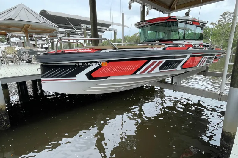 Slide: The Image of 2021 Axopar 28 Cabin boat with vibrant red and black design, docked at a marina. - 4